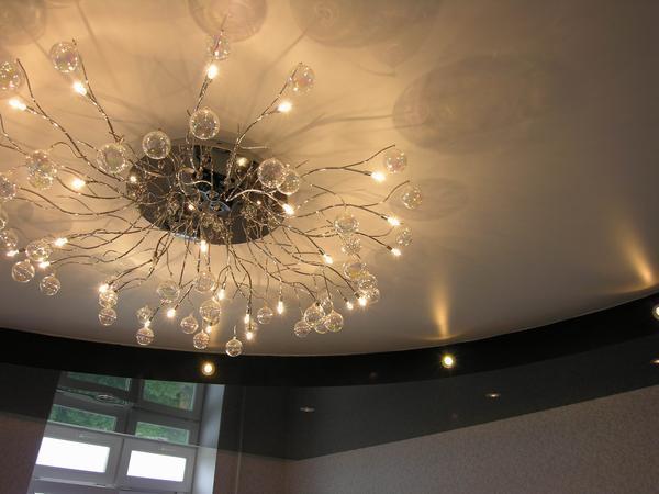 Для создания максимального эффекта при обустройстве натяжных потолков дизайнеры нередко сочетают точечные светильники с люстрой
