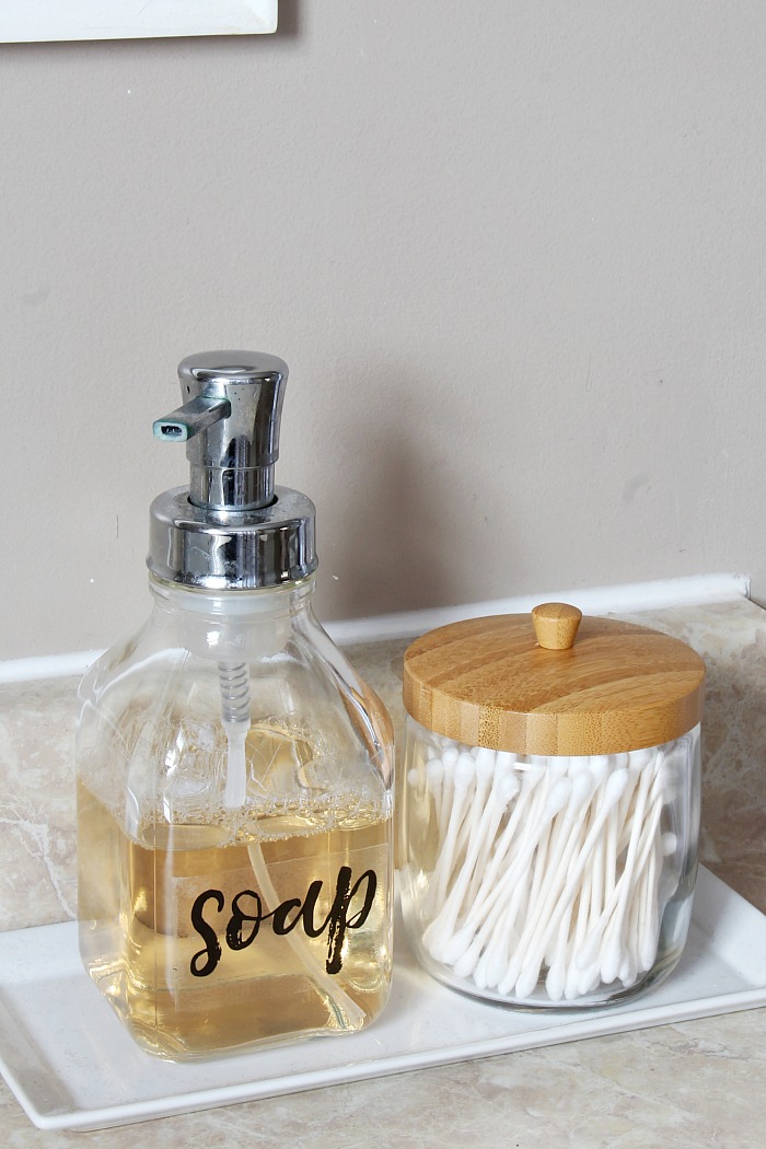 Labeled soap foam dispenser with glass jar of q-tips.